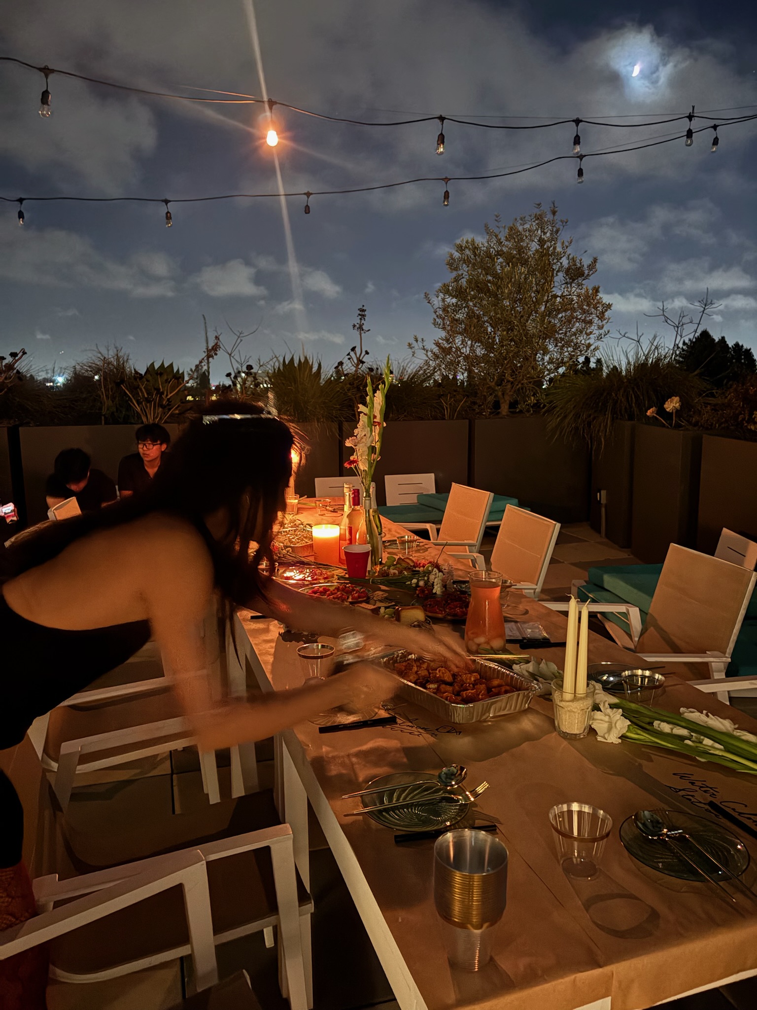 A candlelit rooftop dinner table set for friends